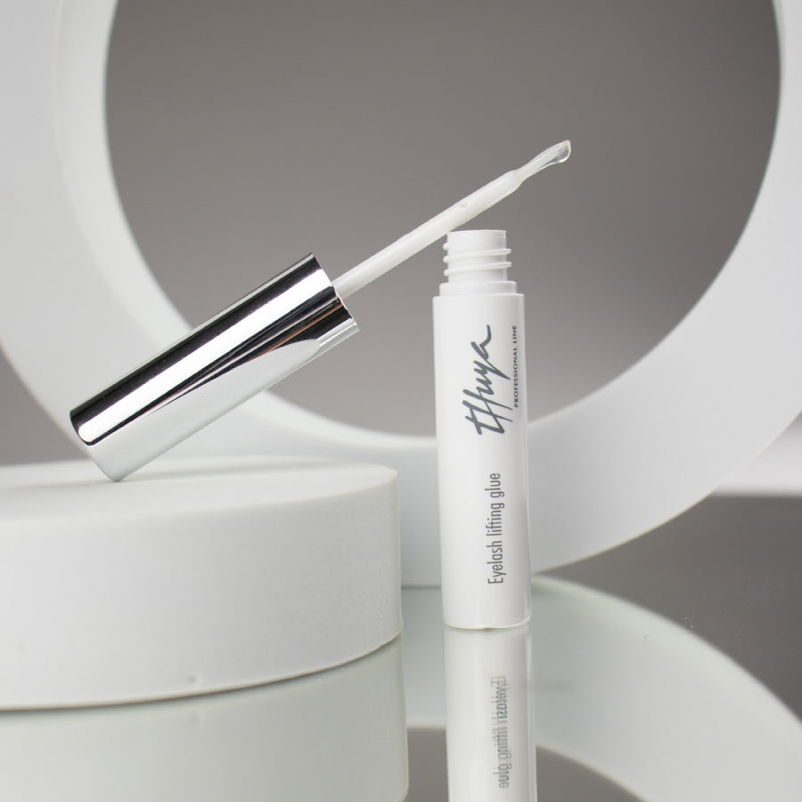 Thuya Eyelash Lifting Glue, clear adhesive for securing lashes during lifts, ensuring strong hold and long-lasting results. small white tube with silver lid, Brush attached to the lid