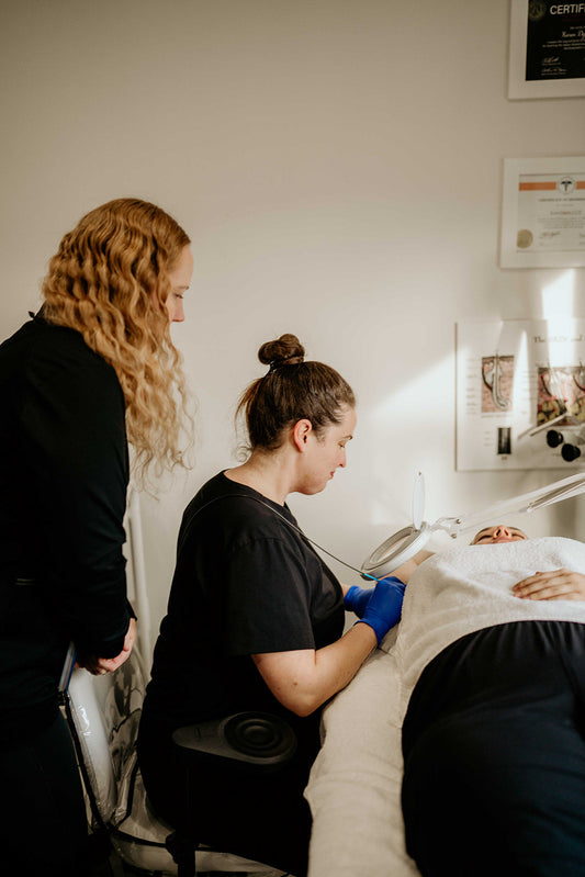 Electrologist working on a client while trainer looks over shoulder