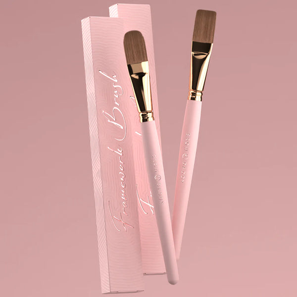 "Brow Daddy Framework Master Brush, available in 2 options, for precise application in brow makeup and microblading, displayed on a clean, pink background , brush aside a box"