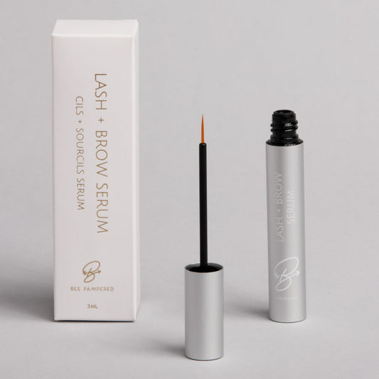Lash & Brow Serum, enhances growth, strengthens, and nourishes lashes and brows. in a cylindrical bottle with a brush inside. vegan friendly 