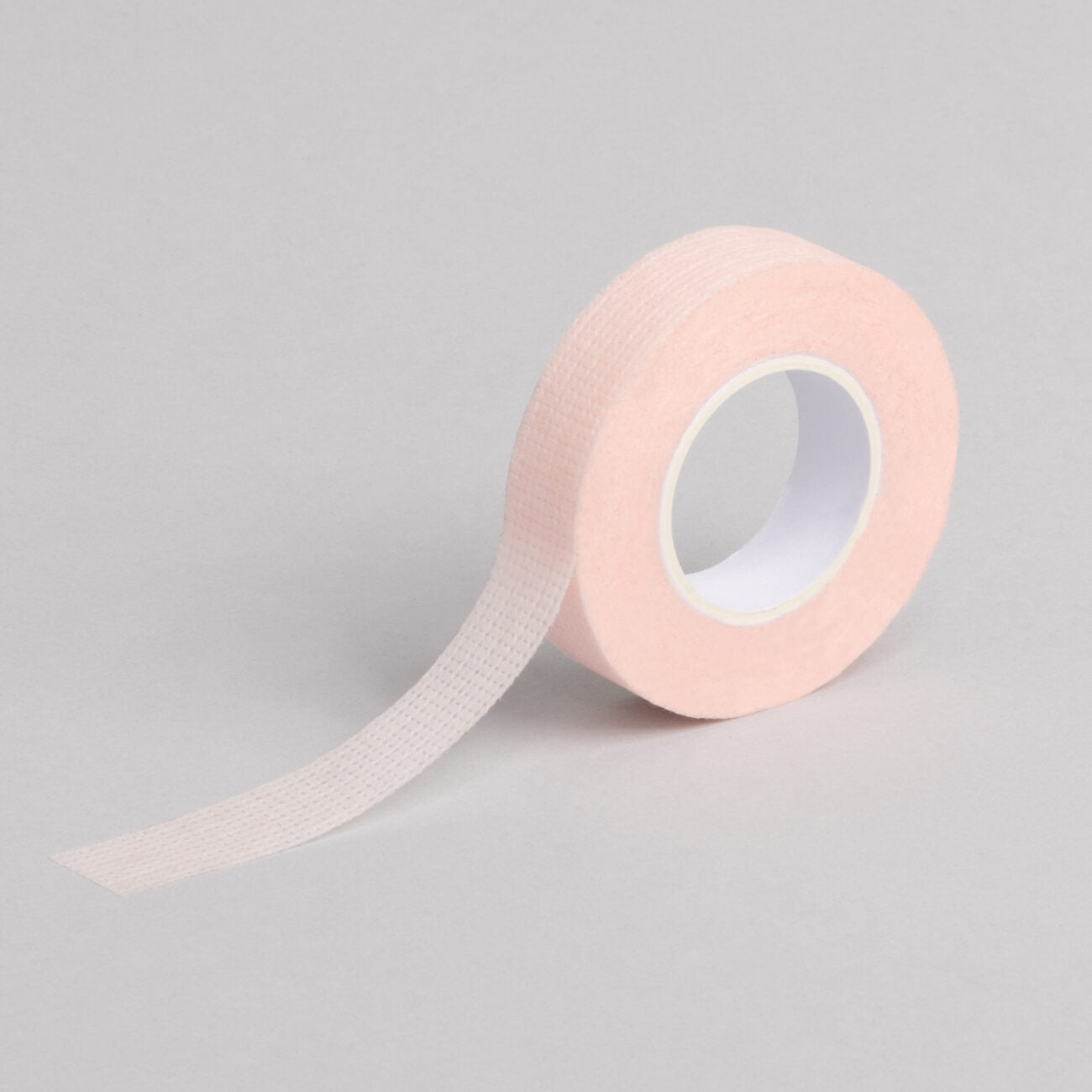 "A roll of pink coloured Bee Pampered Lash Tape, ideal for securing and protecting lashes during extensions or treatments, with a sleek and professional design, displayed on a clean, neutral background."