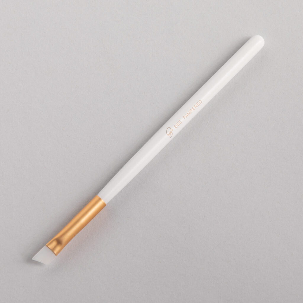 A sleek silicone brush with a flexible, soft tip for precise application of beauty products, brow, lash, and skincare treatments, displayed on a clean, neutral background.